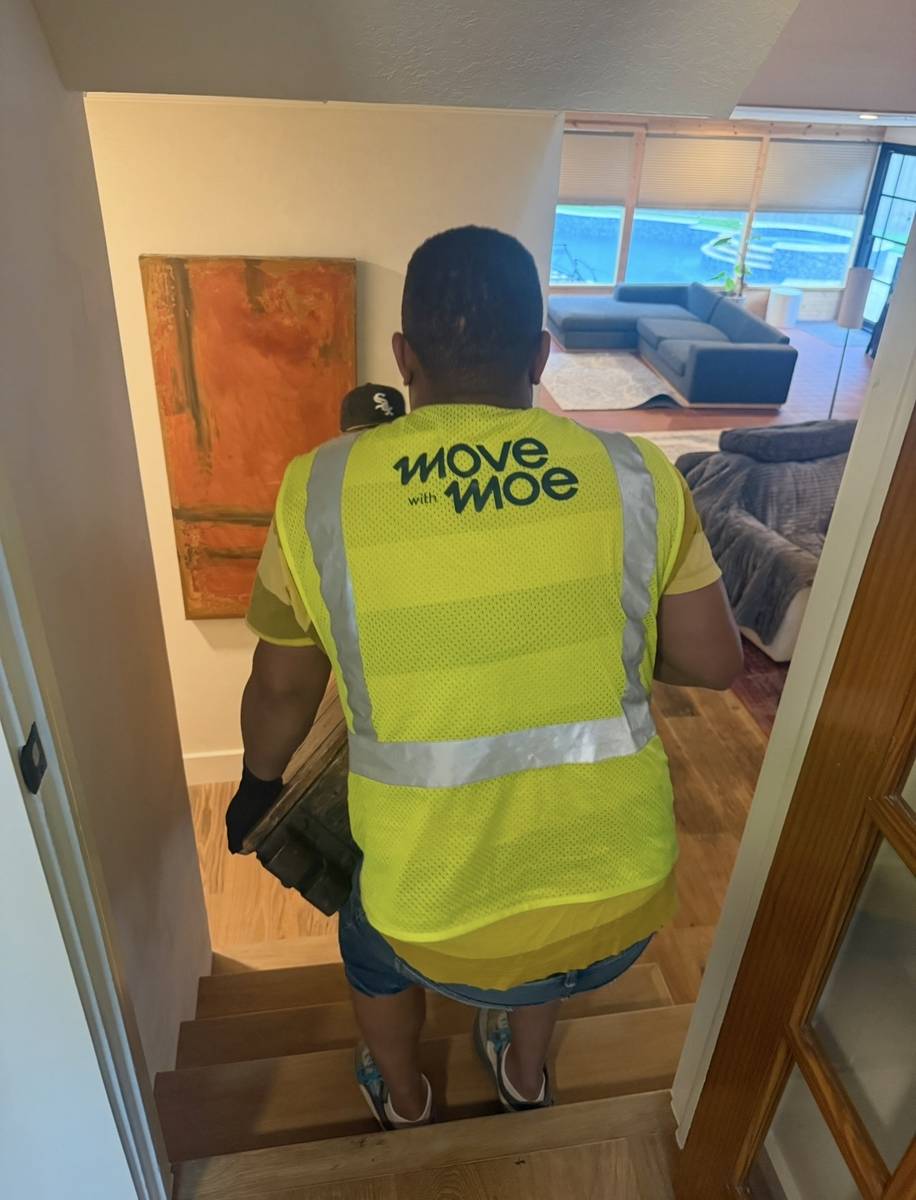 Movers carrying furniture down a narrow apartment stairwell