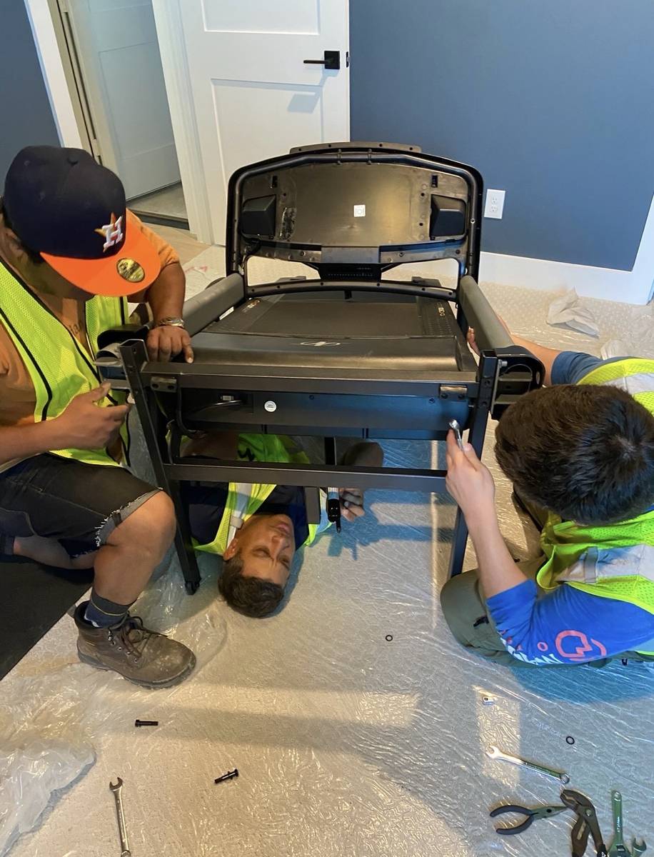 Movers taking apart a piece of gym equipment