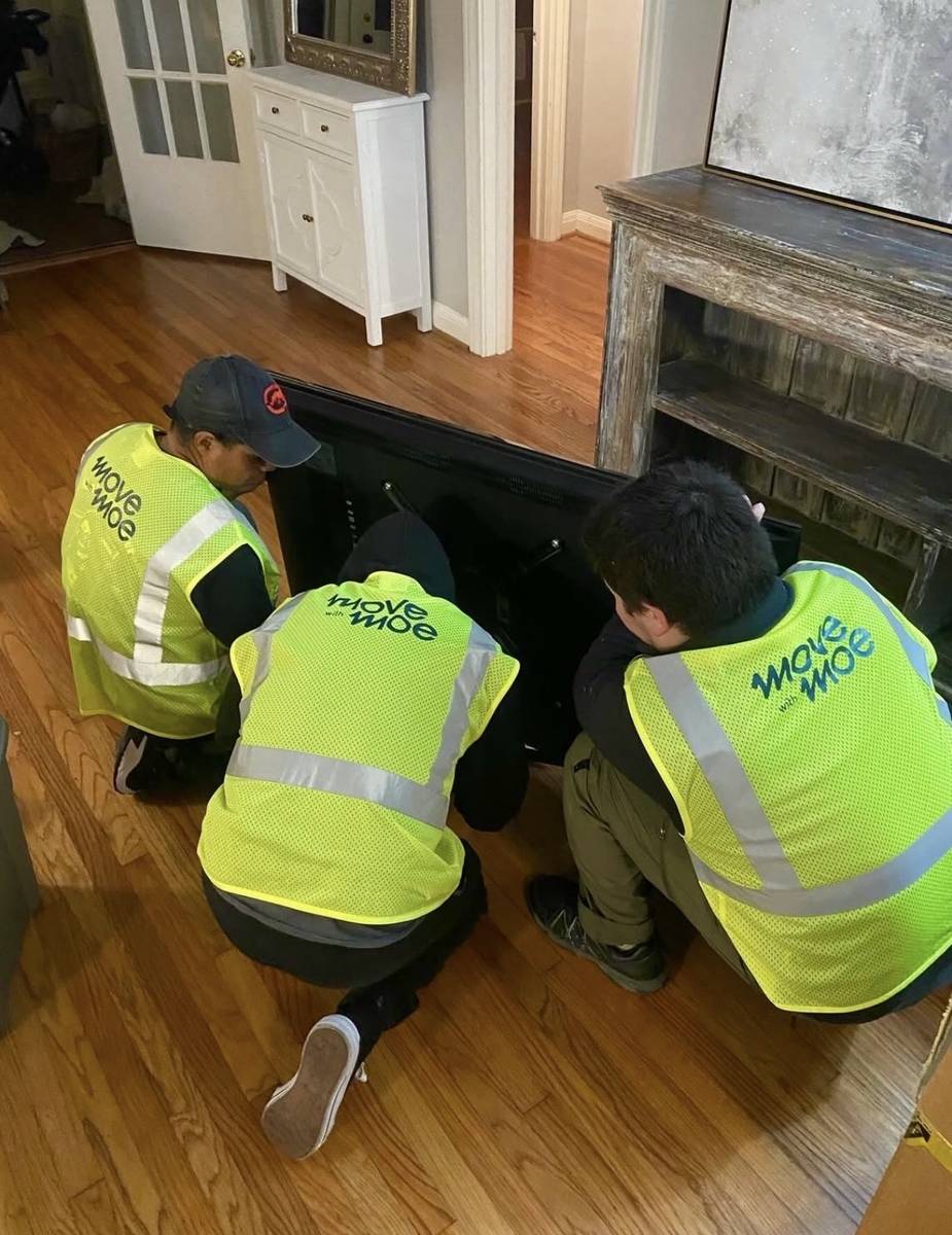 Three movers setting furniture in place in a new home