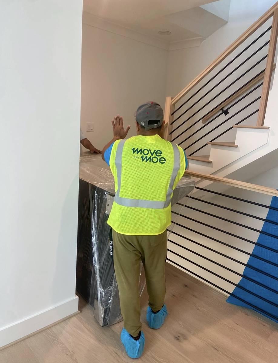 A mover carrying a large item up a modern staircase