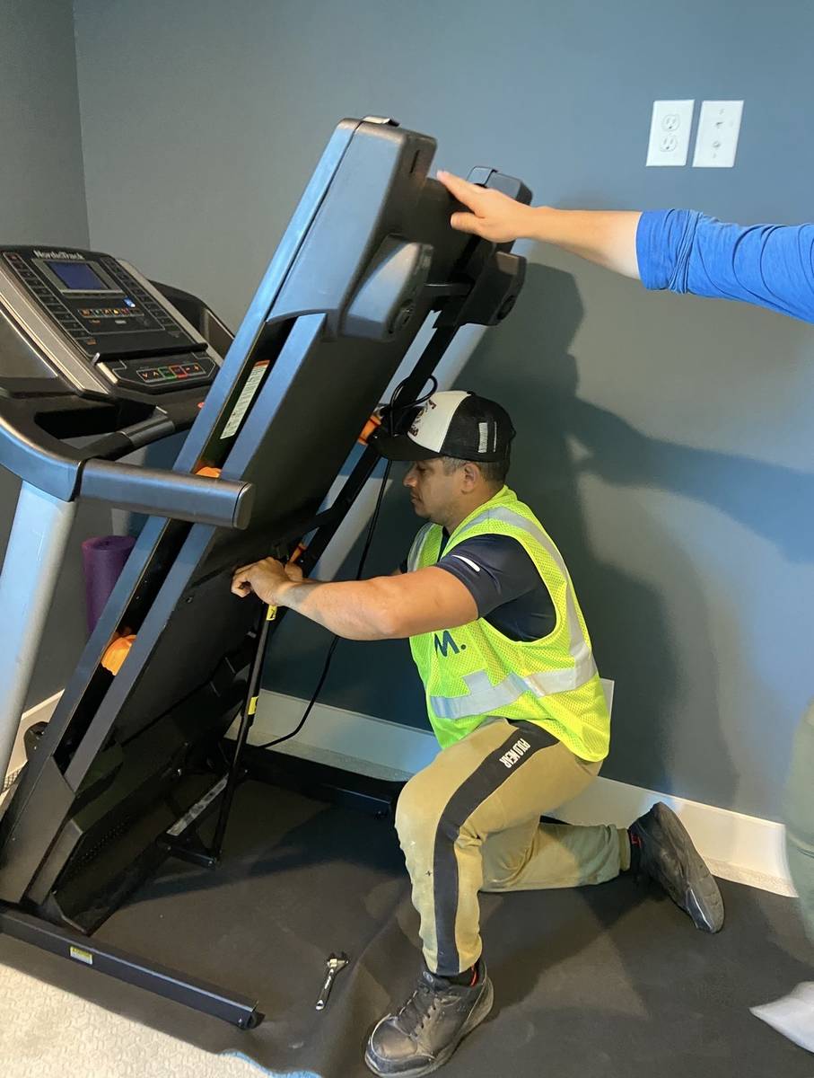 A mover carefully moving a treadmill