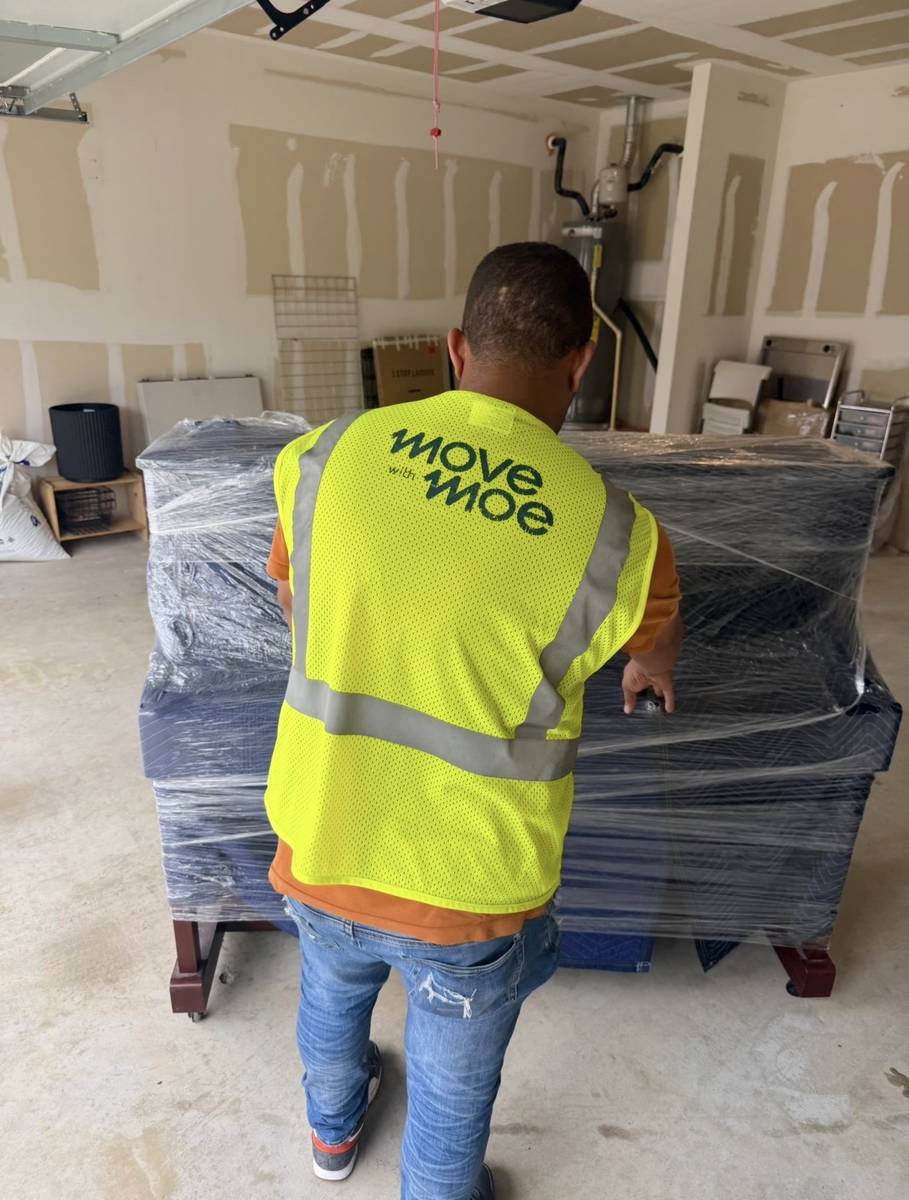 A mover beside fully wrapped furniture ready to load