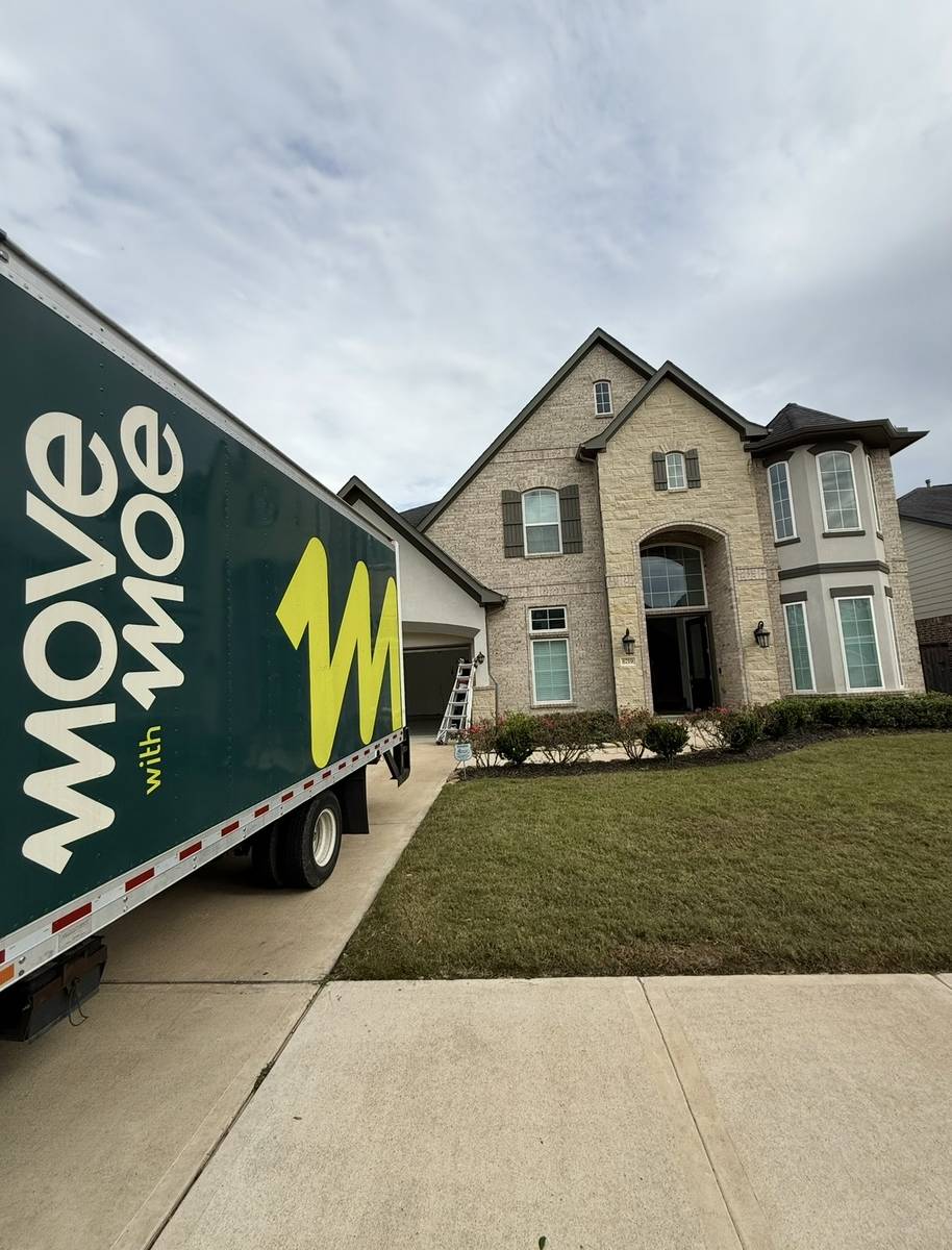 The Move with Moe truck parked outside a large brick home