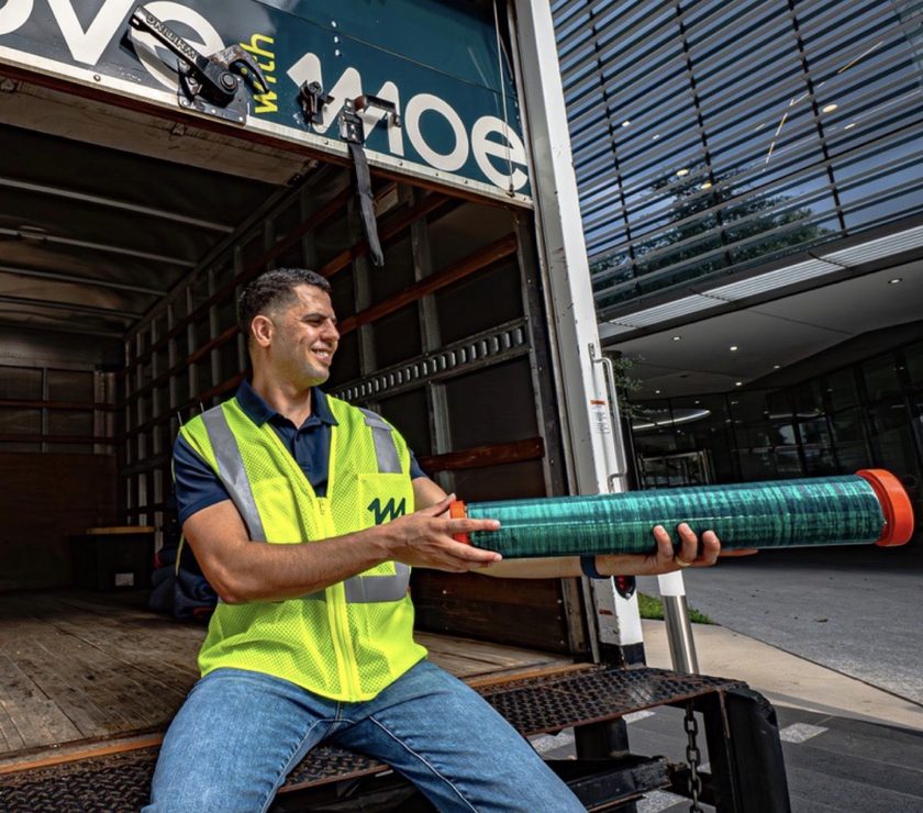 Moe loading a wrapped rug into the truck